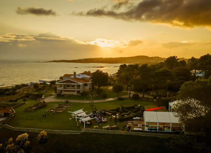 Vista aérea de los jardines de Finca La Atlántida al atardecer, con el océano Atlántico al fondo