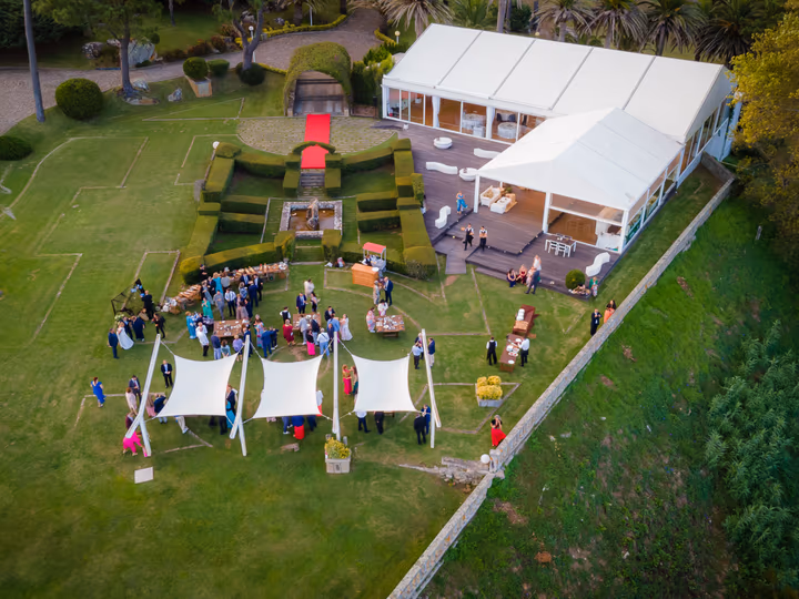 Jardines de la finca con la sala acristalada y los invitados durante el aperitivo
